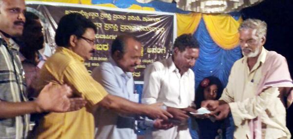 Writer Devanur Mahadeva presenting the award to Somanna at Motta haadi near H.D. Kote in Mysuru district on Saturday. 