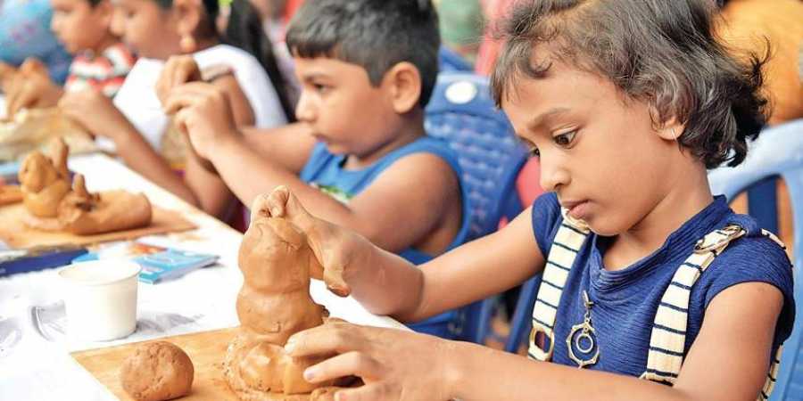 Children try their hand at moulding a Ganesha idol at National College Grounds in Basavanagudi, on Sunday. People from various walks of life and all age groups participated in the event to create a new record of the most number of people sculpting with model clay | Meghana Sastry